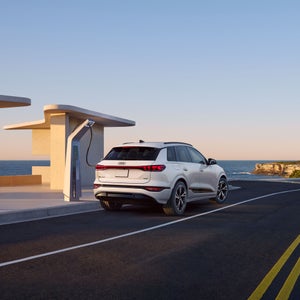 Three-quarter rear view of the Audi Q6 e-tron, parked and charging.