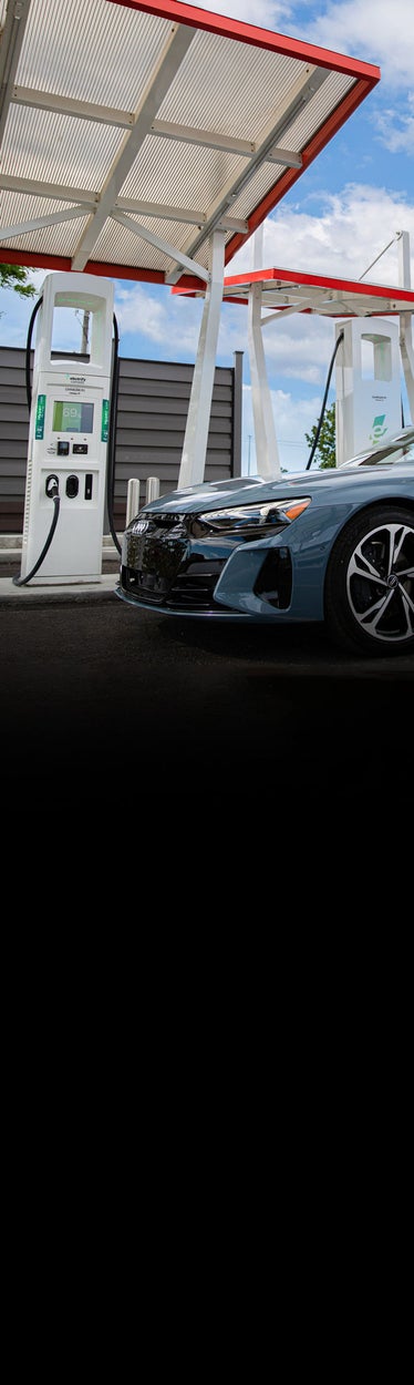 Close-up side profile of a blue Audi e-tron GT parked at a charging station.