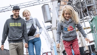 A mother and father walking behind their daughter. 