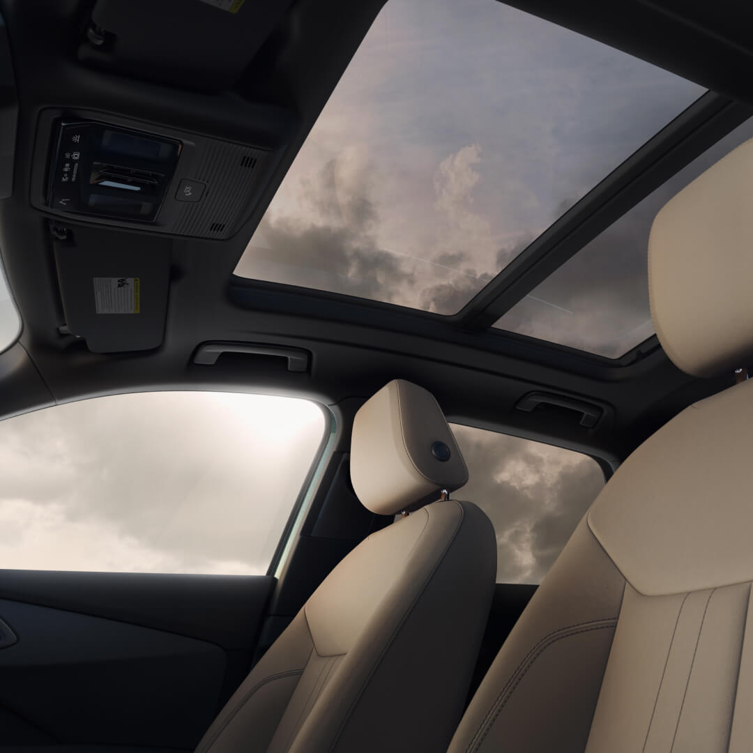 Low-angle interior view of beige front seats and panoramic glass sunroof in a 2026 Audi Q3.