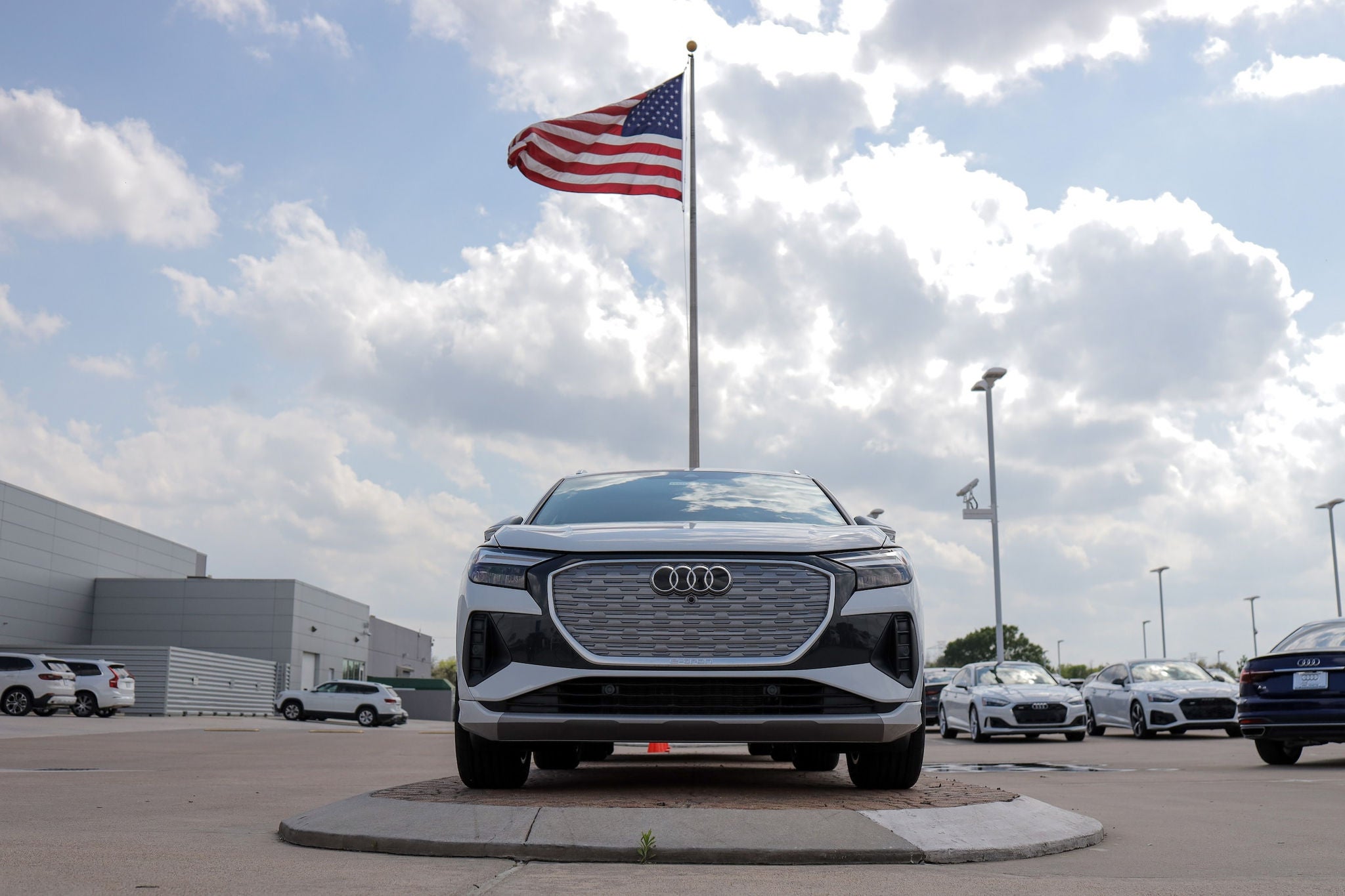 Audi sedan parked in front of dealership, with American flag waiving.