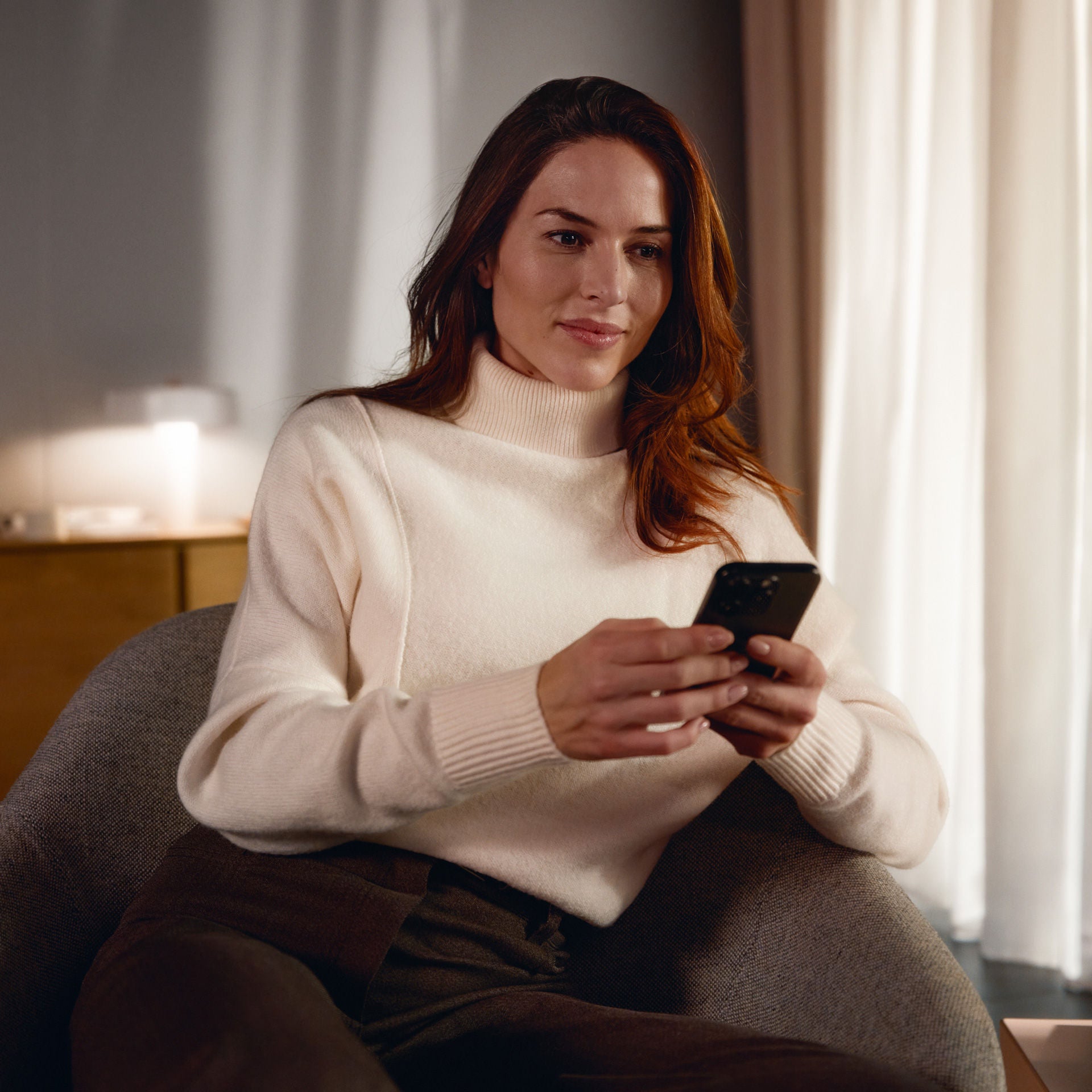 A person sitting at an Audi dealership, using their smartphone.