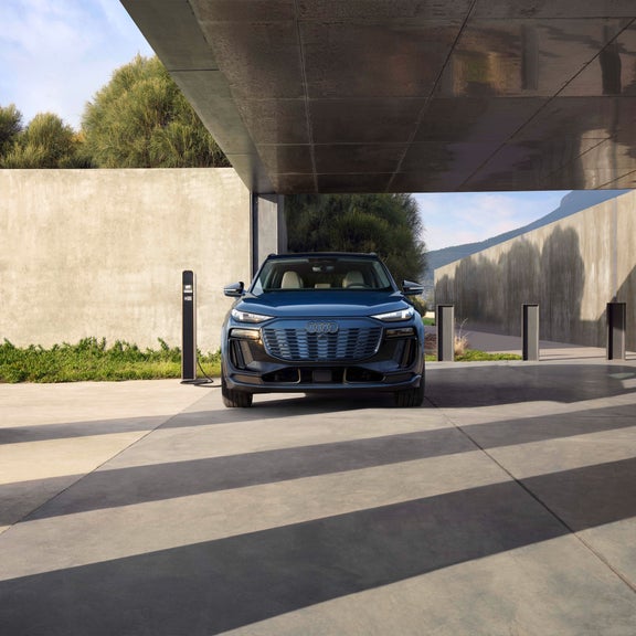 Front profile of a blue Audi Q6 e-tron parked and charging.