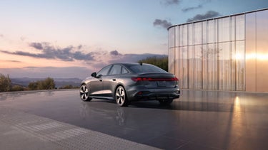 Three-quarter rear view of the Audi A5 parked by a modern building.