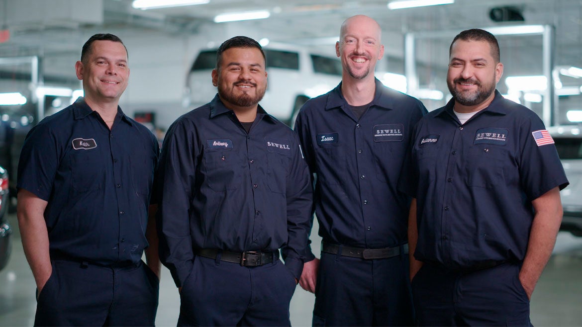 Smiling automotive technicians working on Audi maintenance and repairs. 