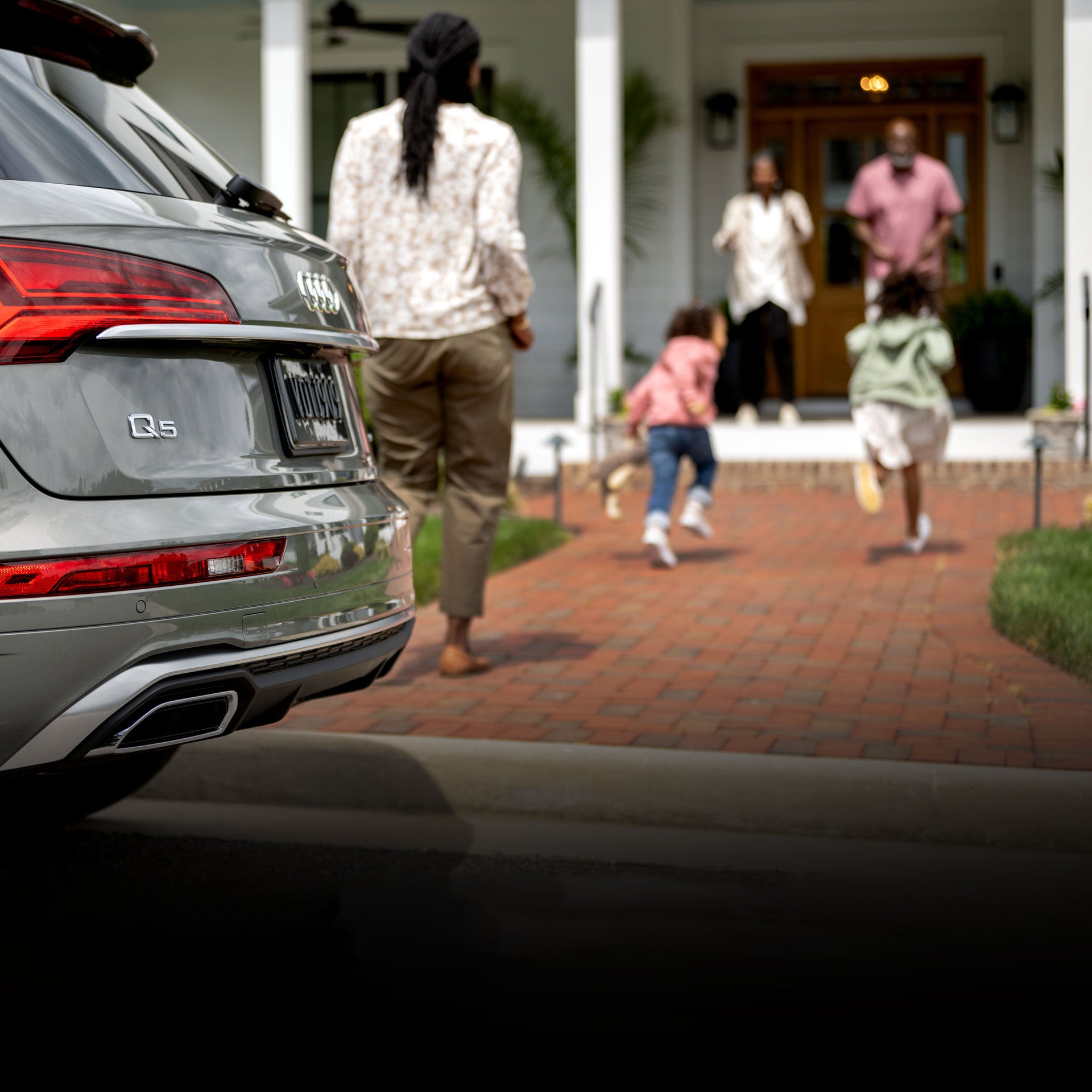 A mother and her young children exiting an Audi on their way to greet their grandparents.