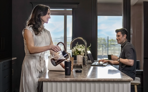 Two people drinking coffee around a kitchen table.