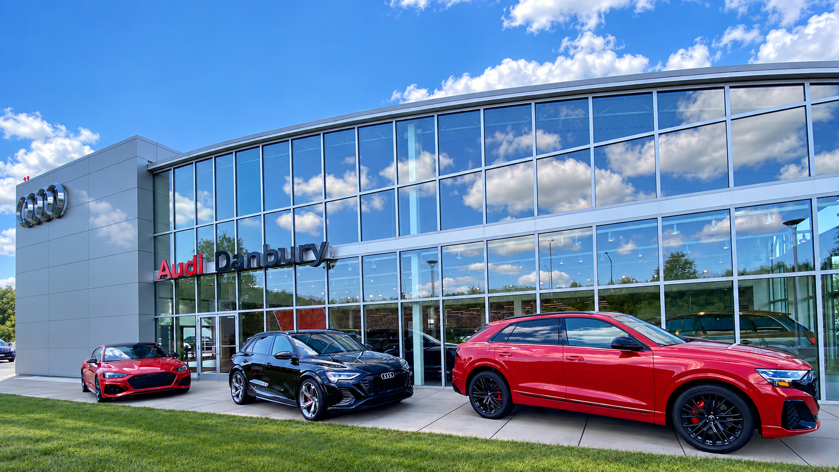 Four Audi vehicles parked side by side with a city skyline in the background.