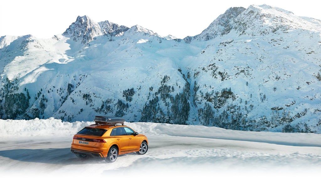 The Audi Q8 driving through a snowy mountainous trail.