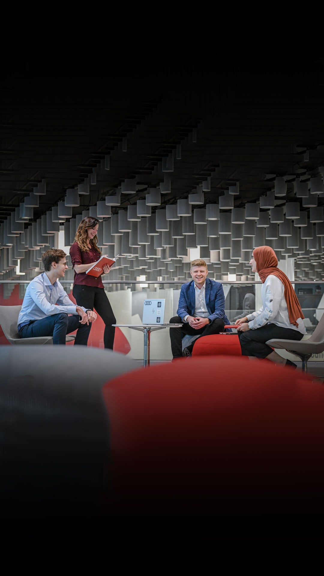 A group of Audi employees gathering around table and talking.