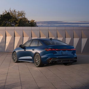 Three-quarter rear view of the Audi S5 parked in front of a modern building.