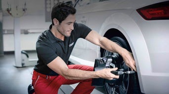 Mechanic loosening lug nuts and repositioning tires as part of a rotation service
