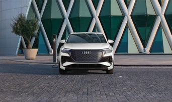 Profil avant d'une Audi Q4 e-tron blanche garée et en charge.