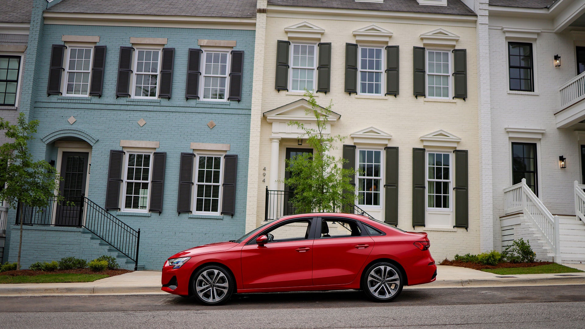Audi sales specialist walking with a customer through the showroom. The sales specialist is handing the customer a key fob for an Audi vehicle.
