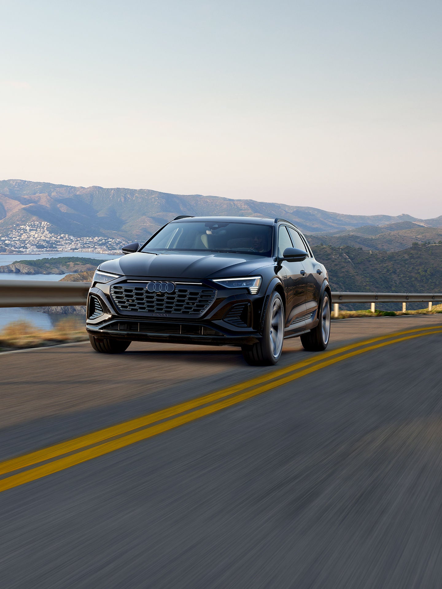 Three-quarter rear view of the Audi SQ8 e-tron parked and charging.