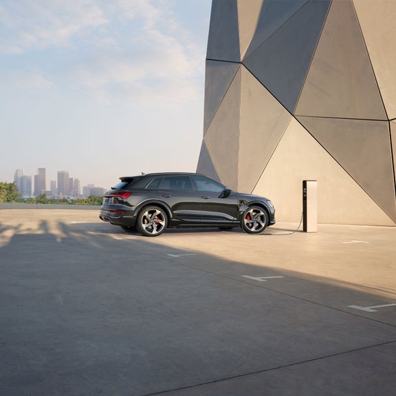 Side view of the SQ8 e-tron parked and charging in front of a city skyline.